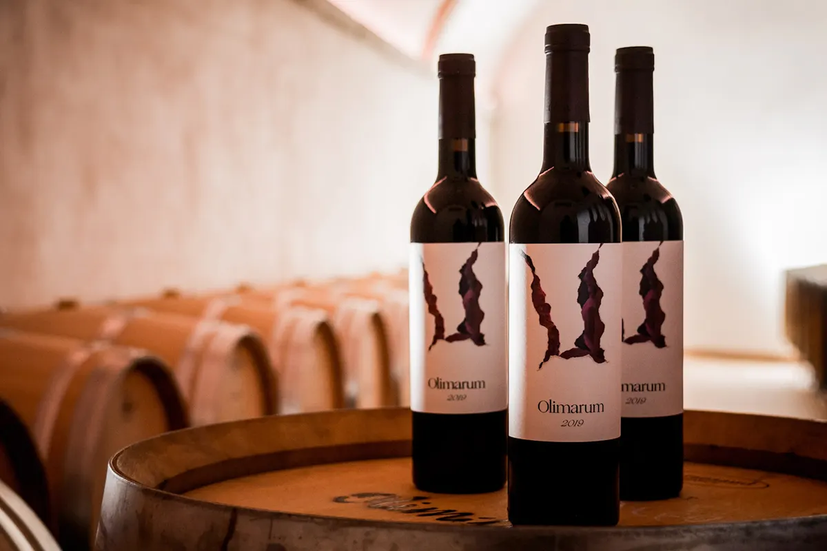 Tres botellas de Olimarum sobre una barrica en la sala de crianza